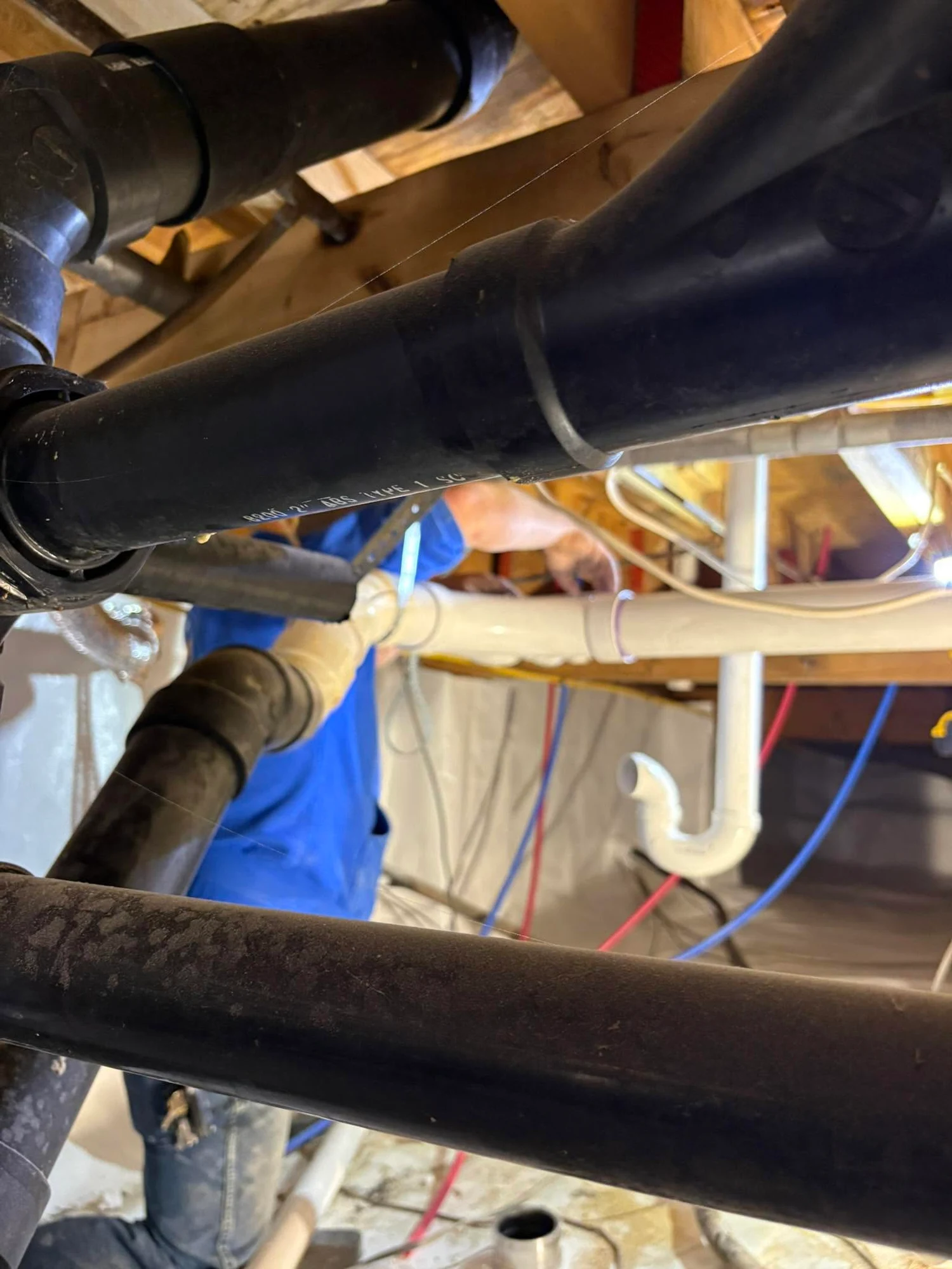 Plumber working on pipes beneath a floor